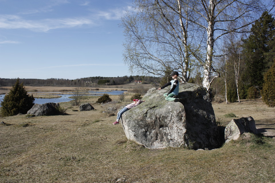 Två barn sitter på ett klippblock. Hagmark leder ned till en våtmark.