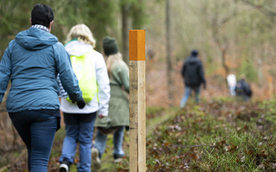 Två personer går längst en stig, en ledskylt är framträdande i bilden
