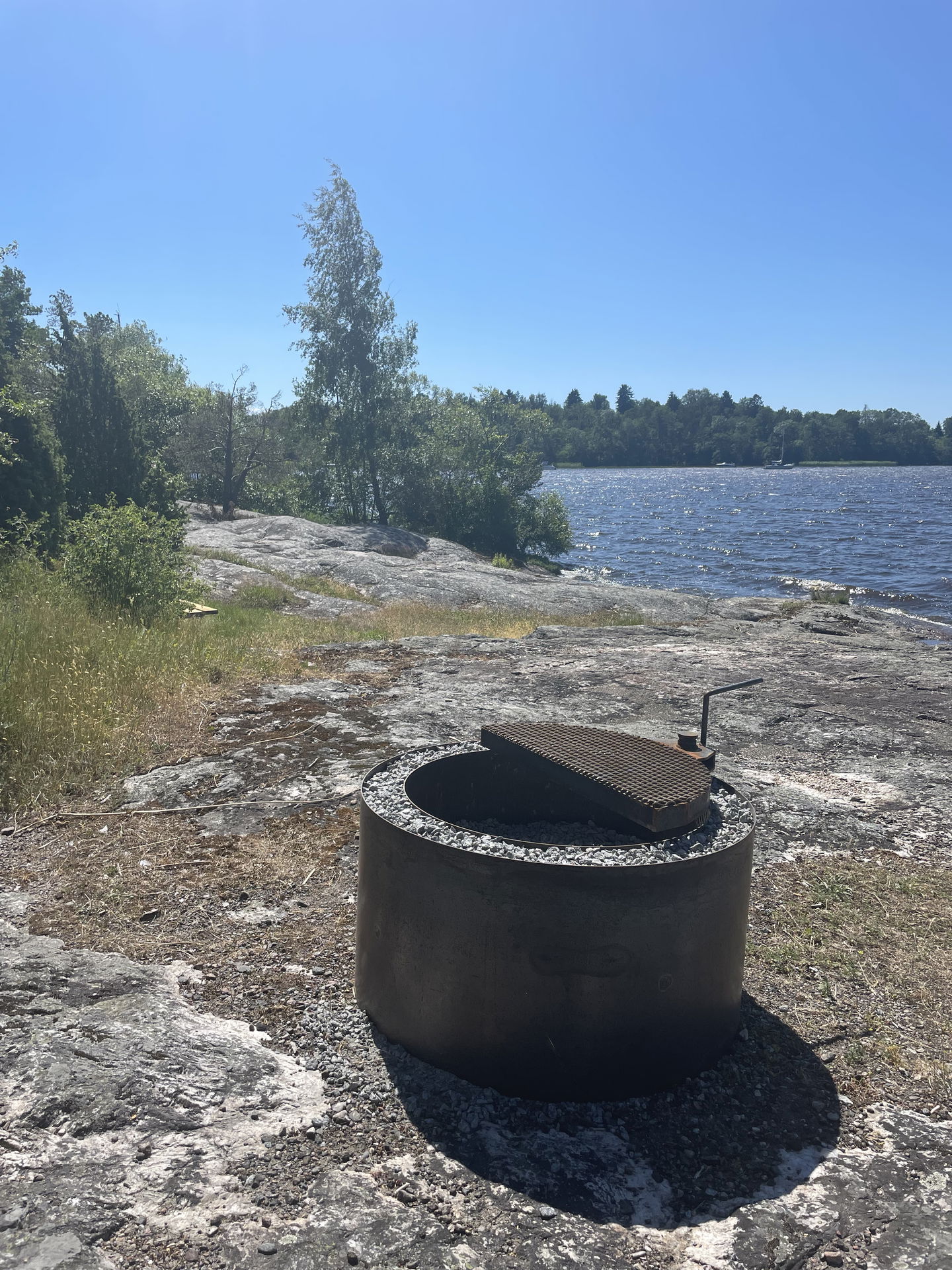 Bild på eldstad och klippor med utsikt över Mälaren.