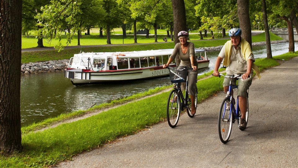 Båt och par som cyklar vid Djurgårdsbrunnskanalen.