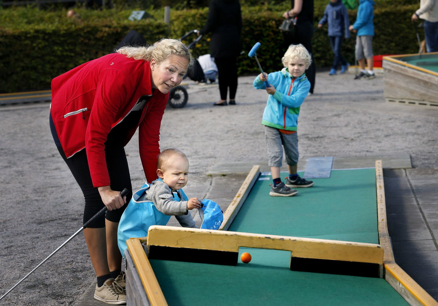 Mamma och två barn spelar bangolf.