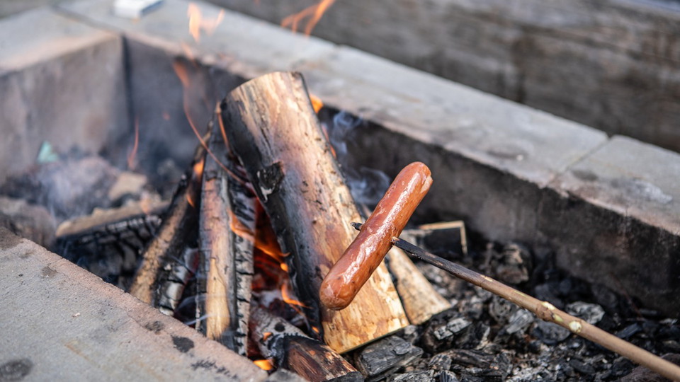 En korv grillas över en öppen eld.