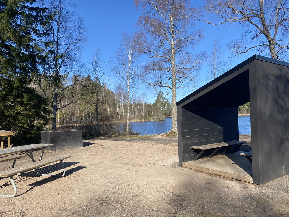 Ett vindskydd vid ett bänkbord och en sjö.