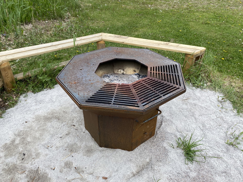 Närbild på grillen med bänk bredvid. 