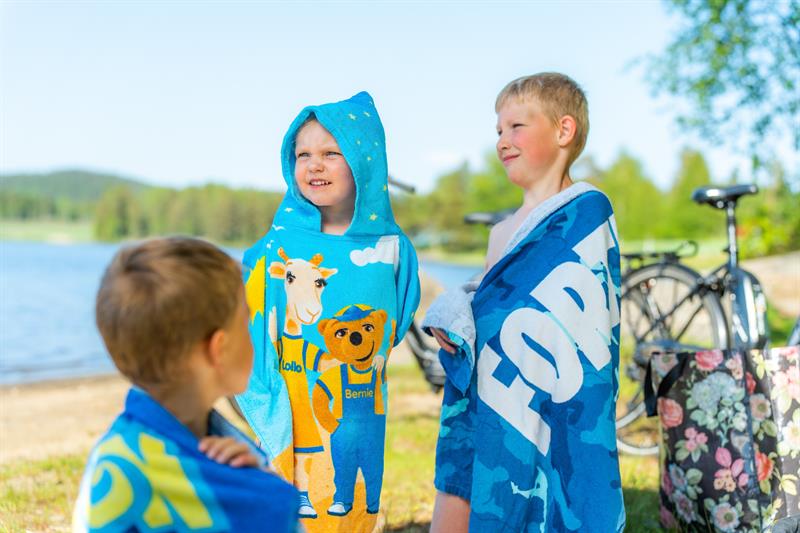 Tre barn pakket seg godt inn i hånduker etter ett bad