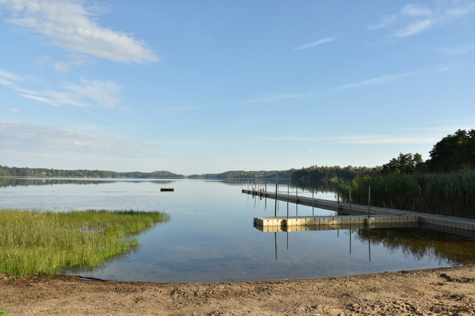 Brygga i vatten och en sandstrand.