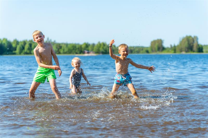 Tre barn har det moro i vannet med sprut og latter