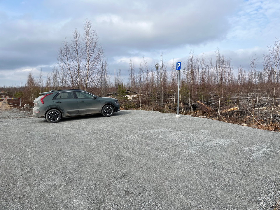Bil parkerad på en grusad yta. En p-skylt.