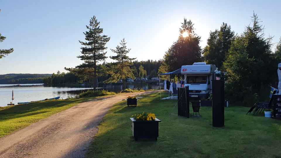 Husbil parkerad intill sjökant. 