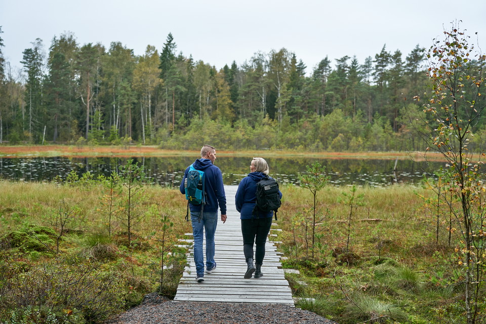 Två personer går på en spång som leder ut till en sjö