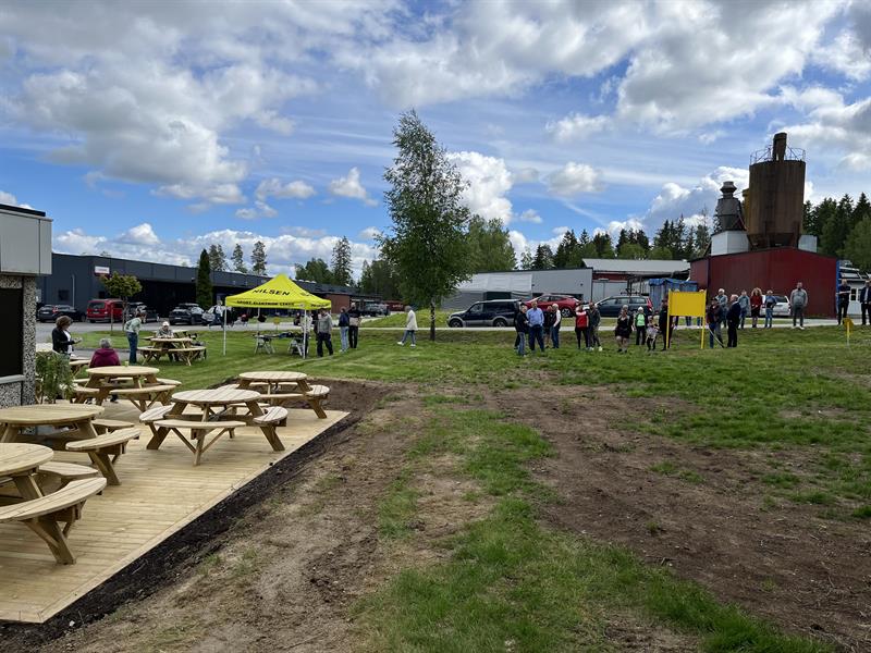 masse mennesker på en gressplen med en platting med sitteplasser ved siden av