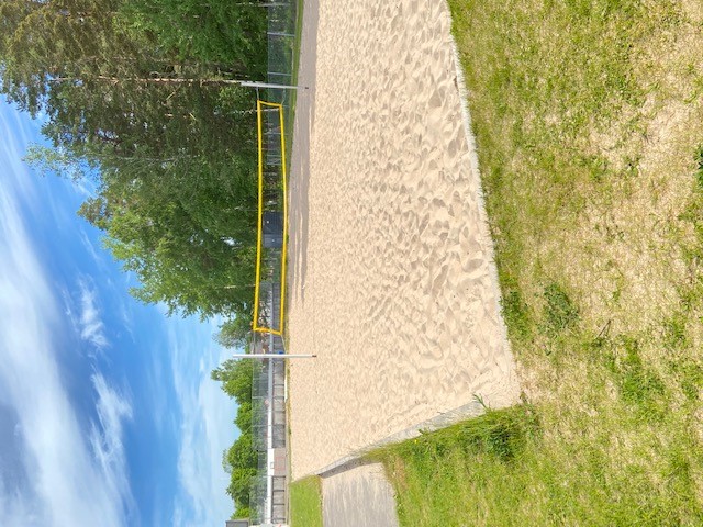 Beachvolleyboll med fin sand som underlag. Nätet svart med gul ram