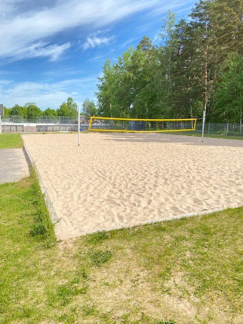 Beachvolleyboll med fin sand som underlag. Nätet svart med gul ram