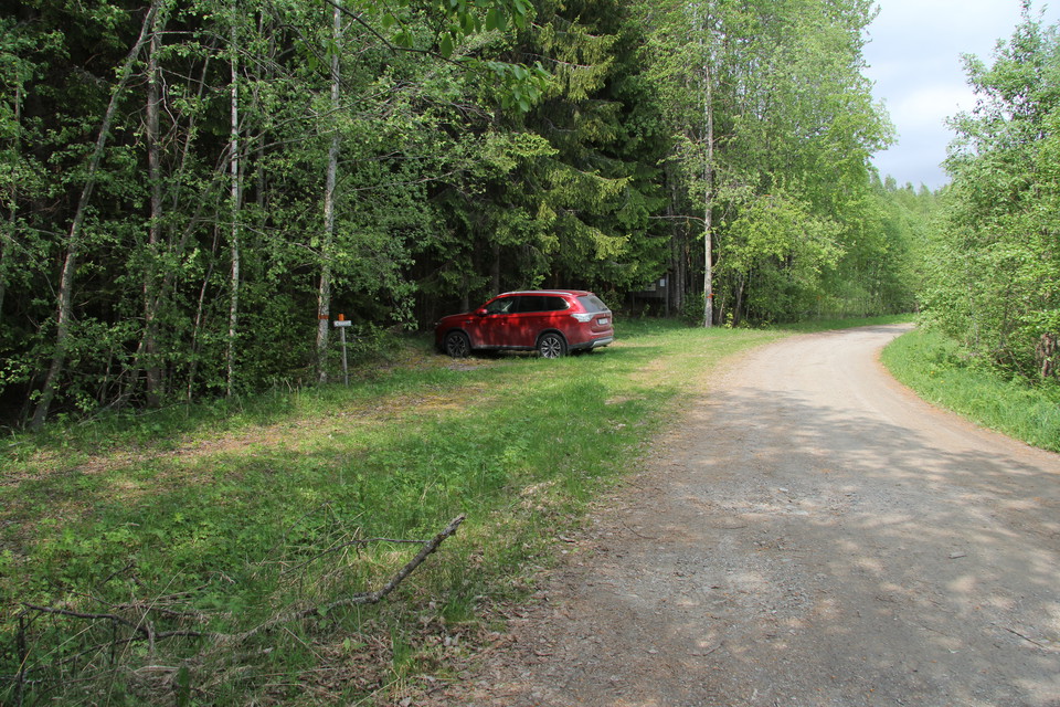 En röd bil står parkerad på naturreservatets parkering.