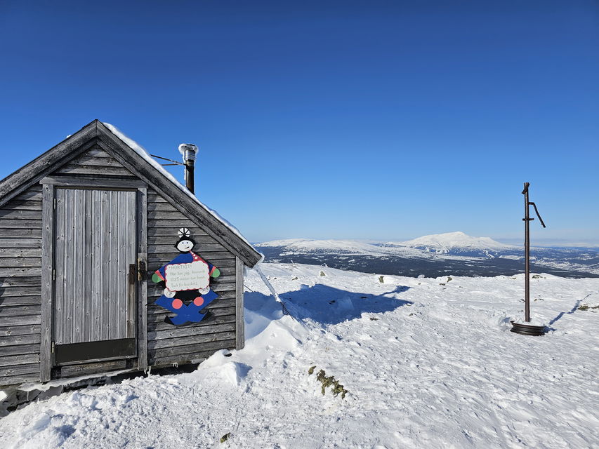 Raststuga på toppen av ett snöigt fjäll med en vy över Åreskutan i bakgrunden