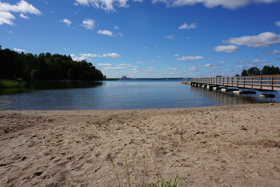 Badplats med sandstrand och brygga som går ut i vattnet