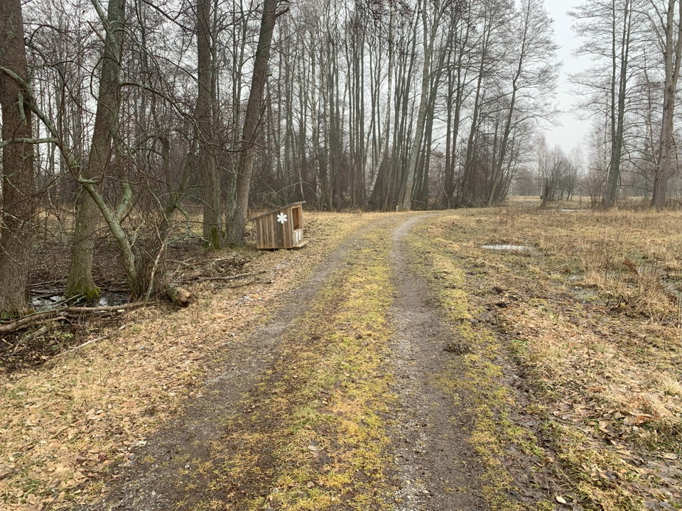 En hård, grusad väg leder fram till vedförråd vid strandängarna i Sandemars naturreservat.