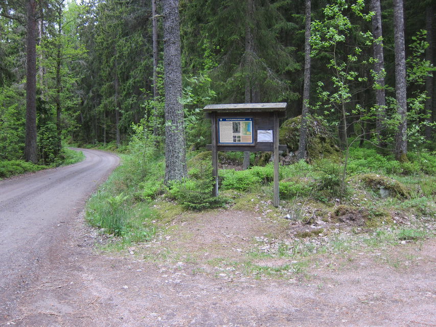 Informationstavla på håll invid grusväg.