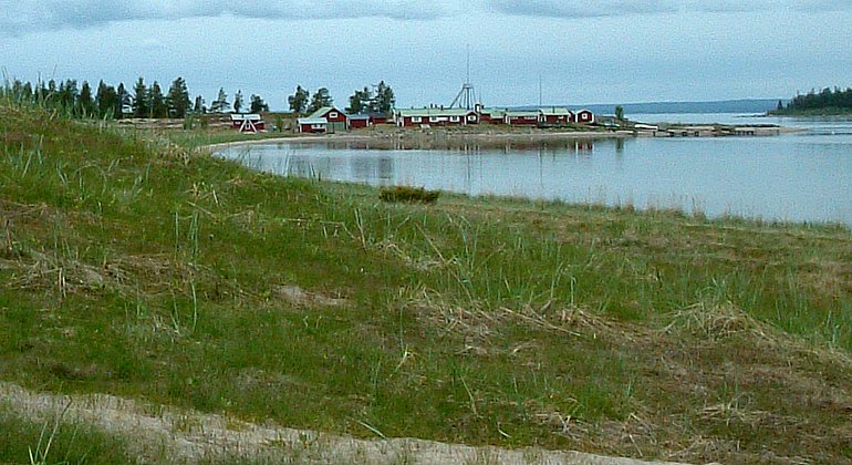Stränder breder ut sig längs ön Stenskär, där det också finns ett fiskeläge med röda stugor.