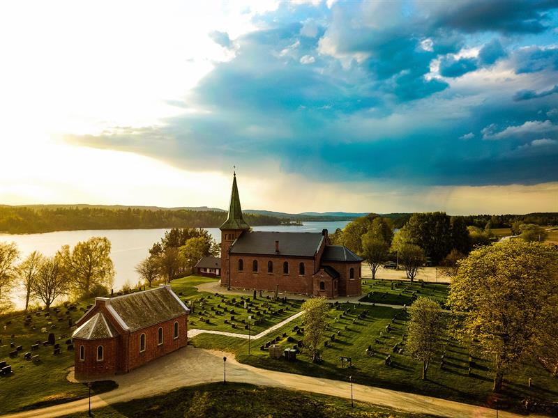 Gammel kirkegård med masse gravplasser og en stor kirke i murstein.