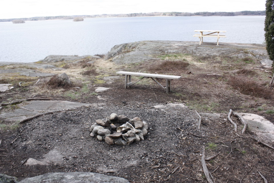 En eldstad. Två bänkar står i närheten.