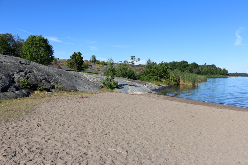 Sandstranden med klipphäll i ena änden.