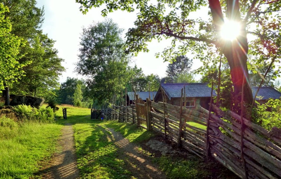 En gammal gård i motljus med gärdsgård