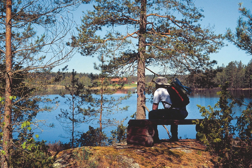 Man sitter på bänk vid sjö