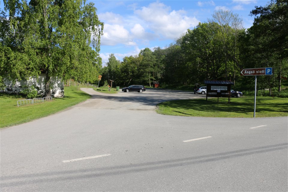 Parkeringsplats med skylt som visar vägen och informationstavlor.