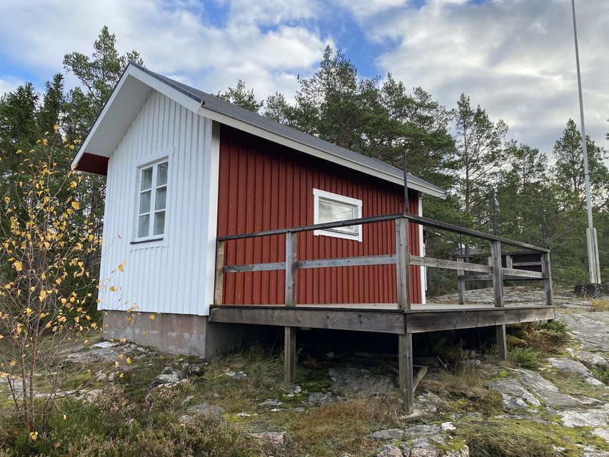 Lotsstugan med vit gavel fotad mot skogen