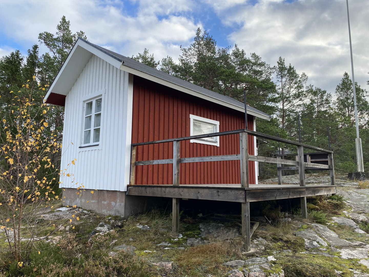 Lotsstugan med vit gavel fotad mot skogen