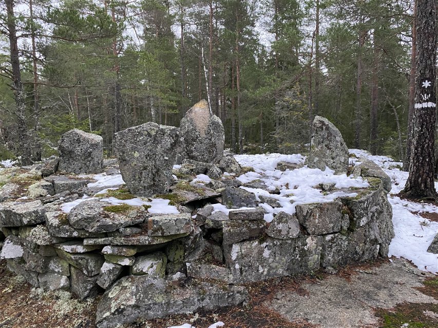 I skogen står flera stora stenar staplade på varandra i en hög.