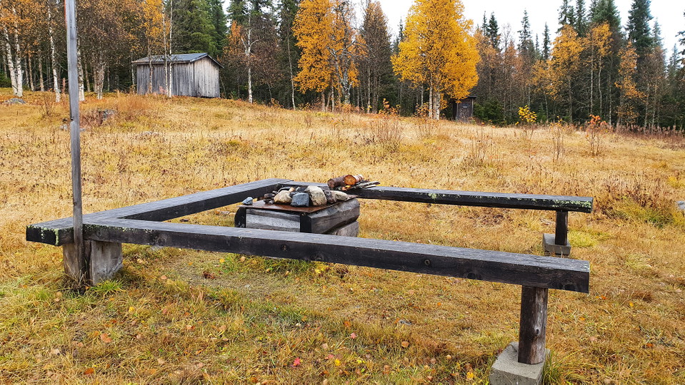 En eldstad med tre bänkar runt. Foto.