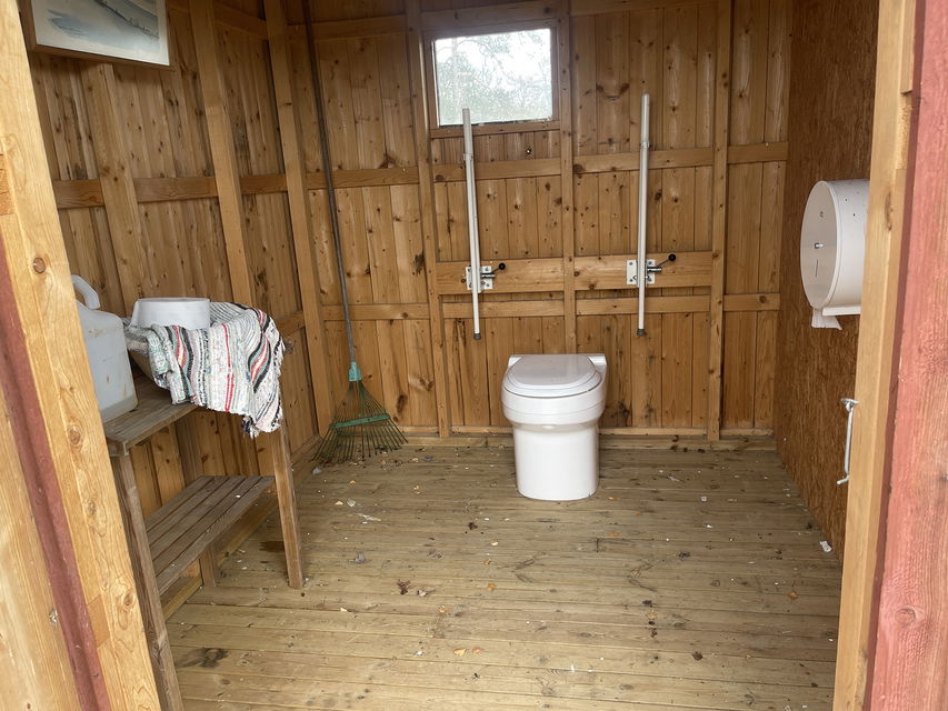 Handikappanpassad toalett i träskjul.