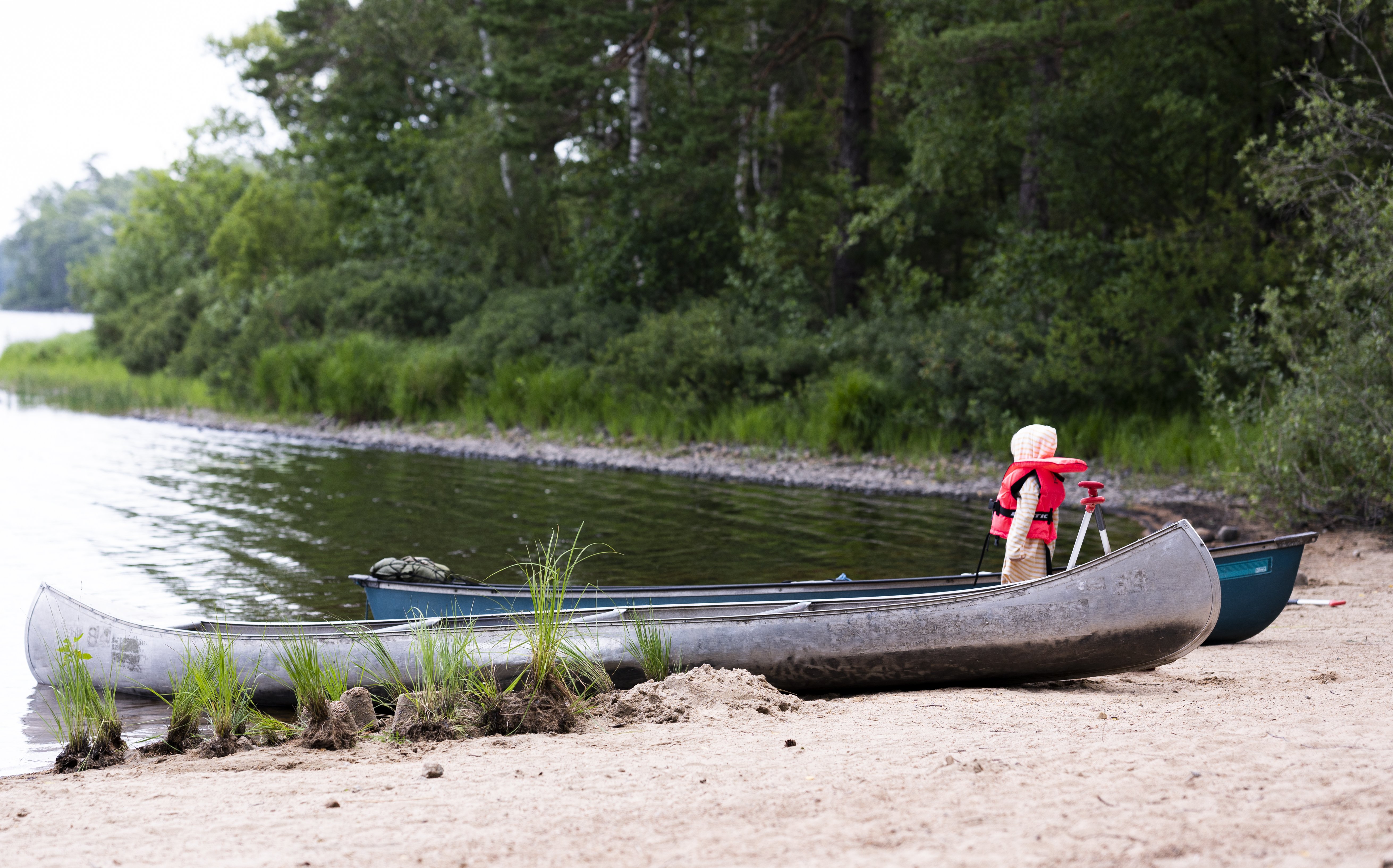 Ett barn står vid två kanoter