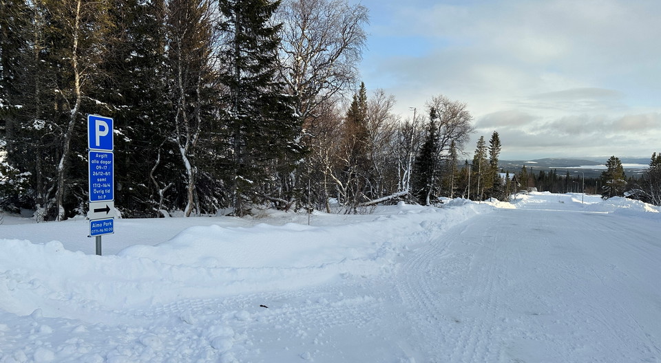 Väg i vinterlandskap med skylt för parkering