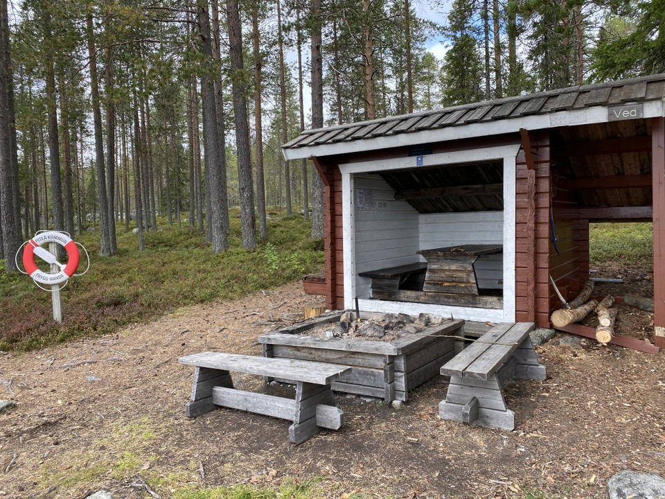Ett vindskydd med en eldstad och bänkar utanför.