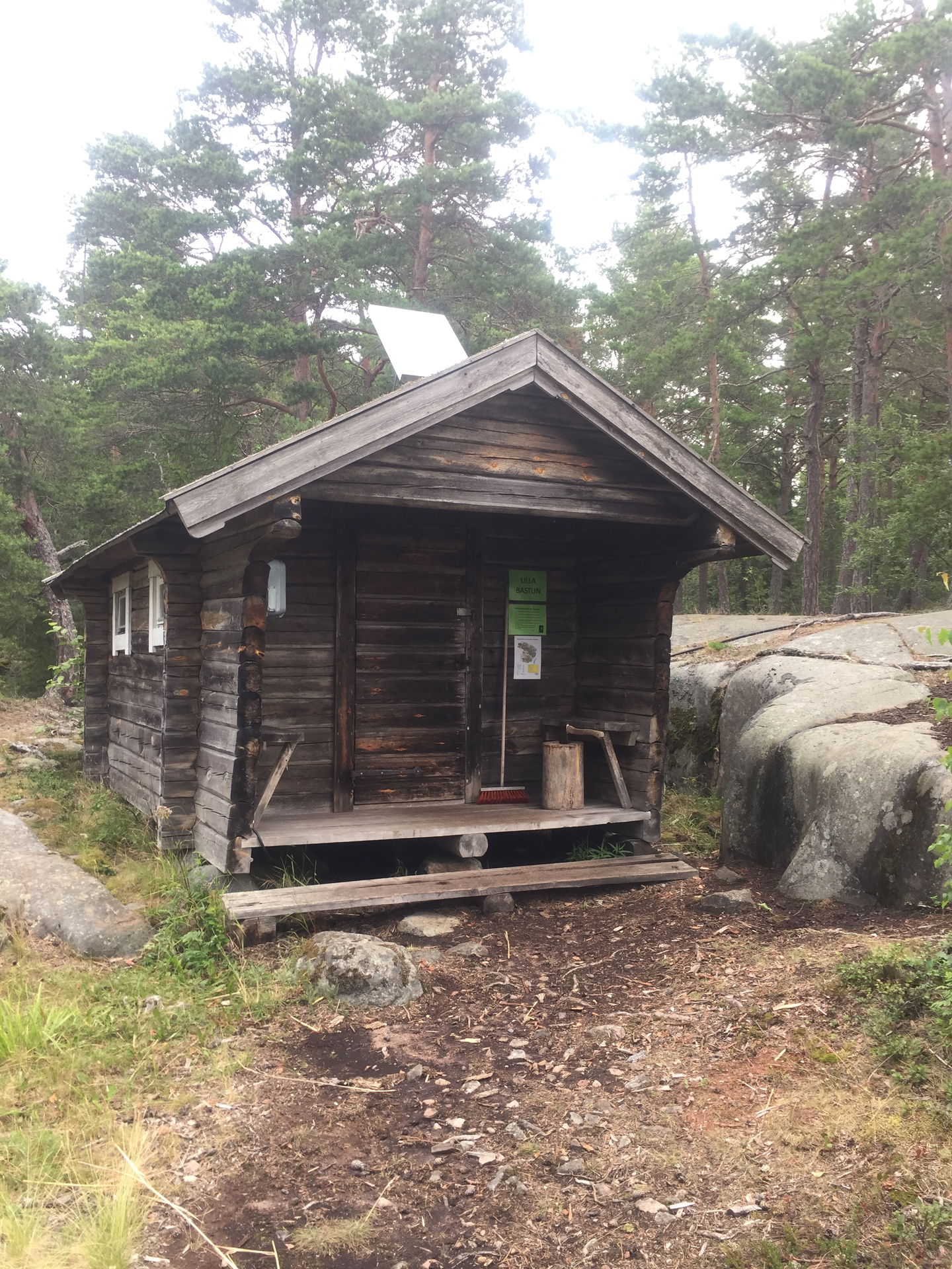 Vid ett klippblock står en byggnad med lågt i tak och två trappsteg upp till entren.
