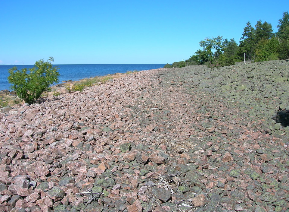 En plan öppen yta vid havet. Ytan är täckt av stenar i olika storlekar.