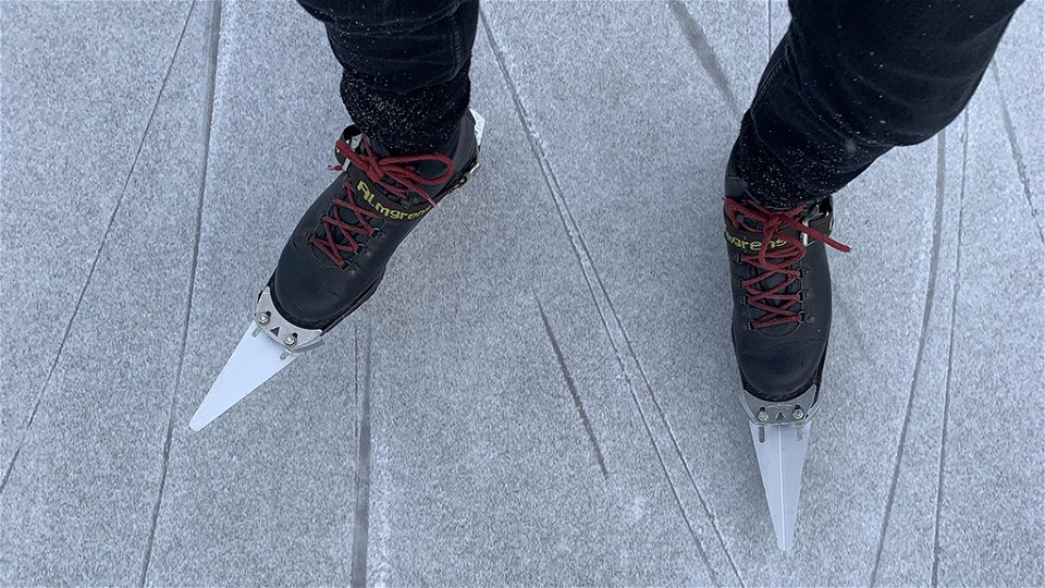 När bild på en persons fötter med pjäxor och långfärdsskridskor om åker på en is.