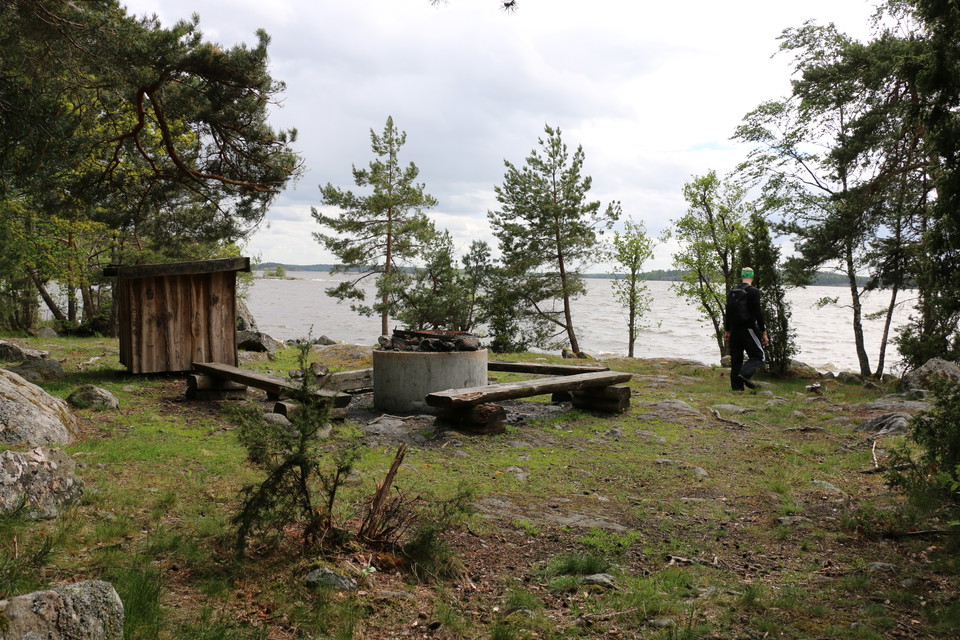 Rastplats intill Mälaren med eldstad, vedförråd och bänkar.