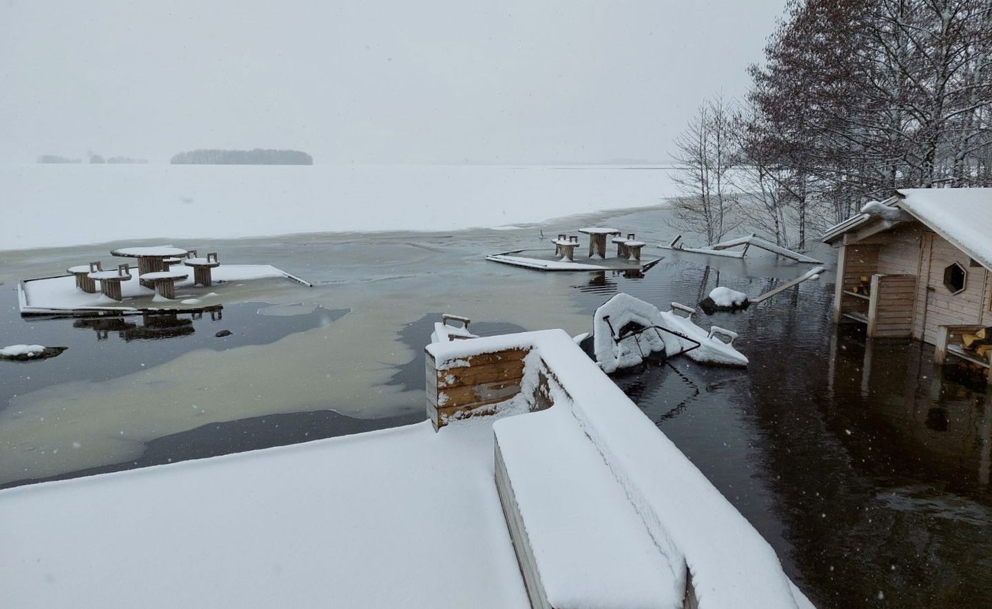 Rastplatsen som ligger under ca 1 meter vatten och is. Det är oordning på platsen. En grillplats har vält omkull, brädor som flyter omkring. 