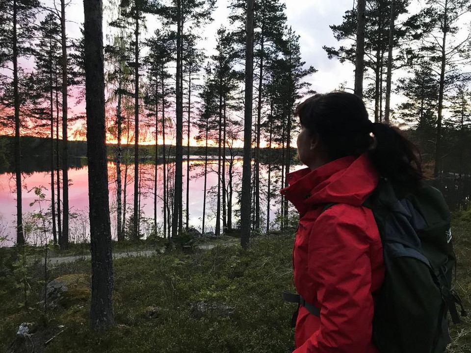 Solnedgång över Bocksjön. En vandrare står och tittar ut över vattnet.