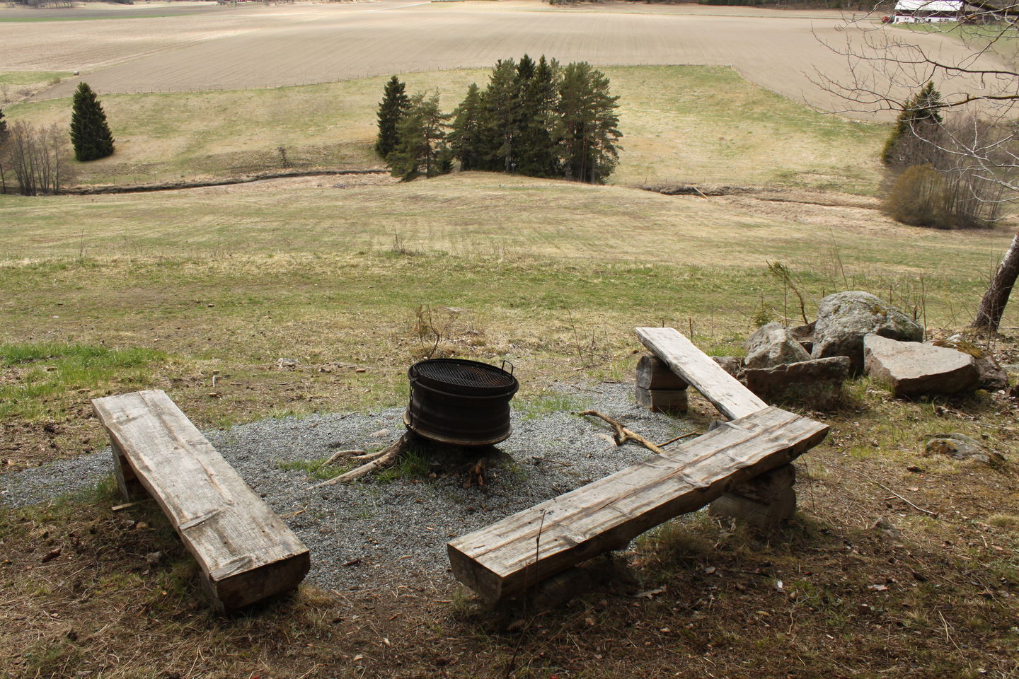 En grillplats med tre sittbänkar står i en brant sluttande backe.