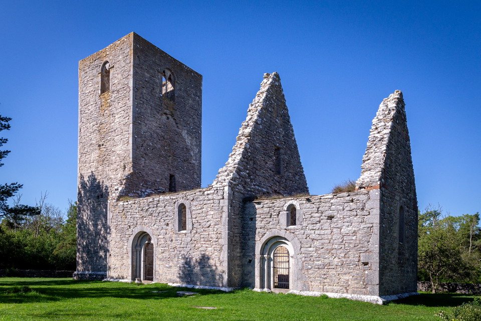 Ruin av stenkyrka på gräsmark.