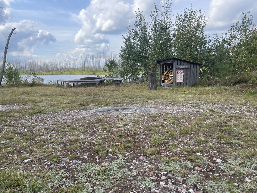 Rastplats med picknickbänk, eldstad och vedförråd.