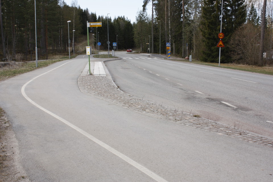 En busshållplats vid en bilväg. Bakom hållplatsen går en gång- och cykelbana.