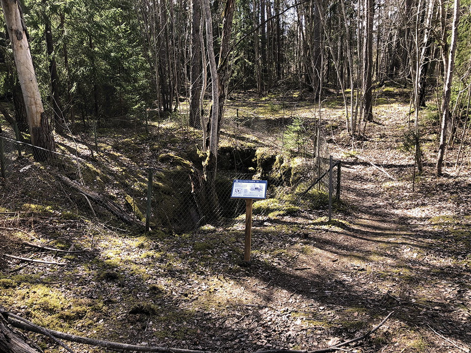 Informationstavla vid inhägnat hål i marken.
