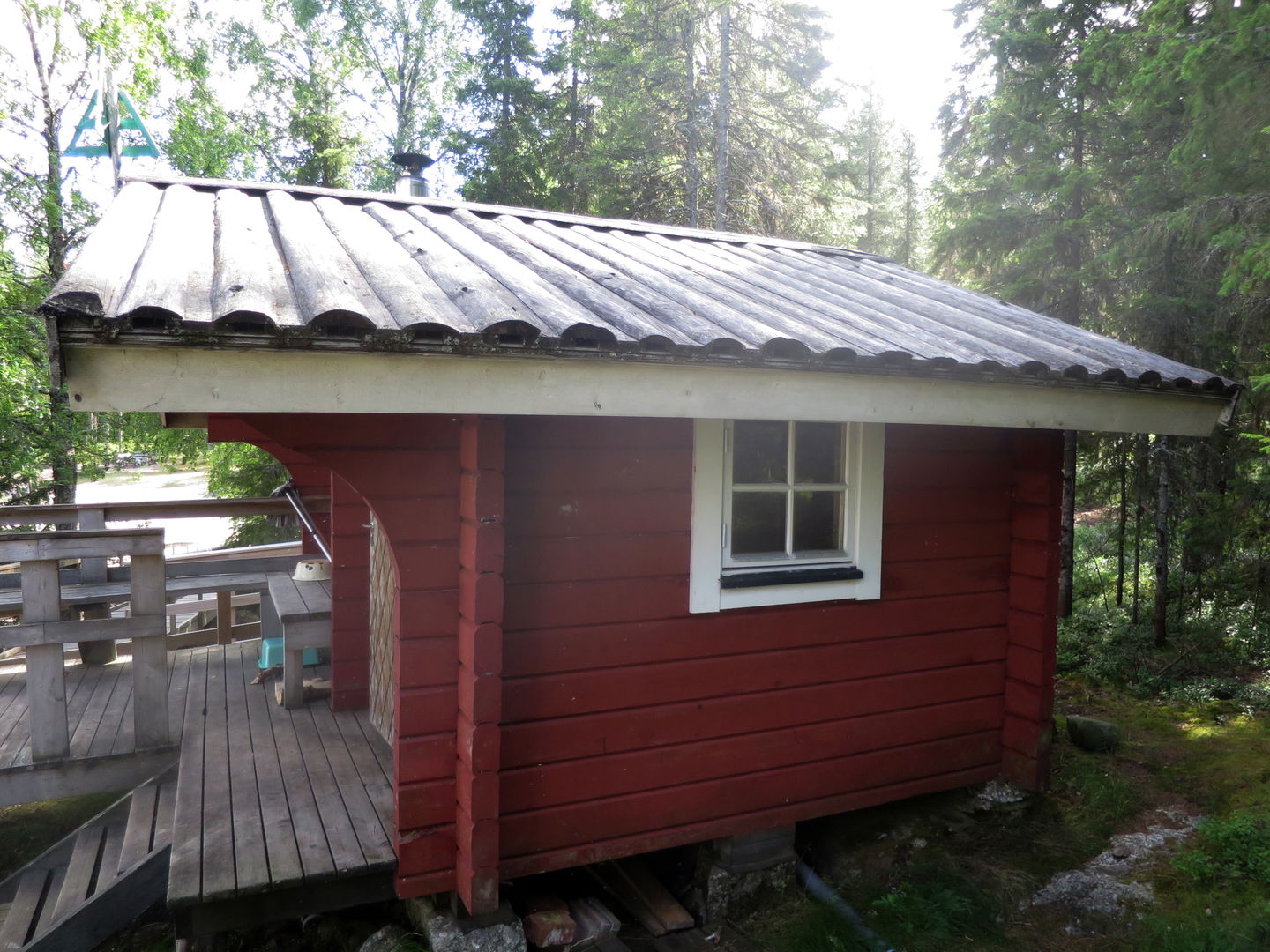 En röd liten träbyggnad med en veranda.