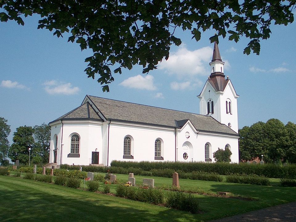 Bild på Högby kyrka med gravplatser i förgrunden